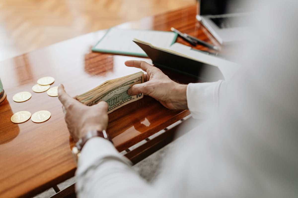 Person-counting-cash-and-coins-on-a-wooden-table-emphasizin1.jpg