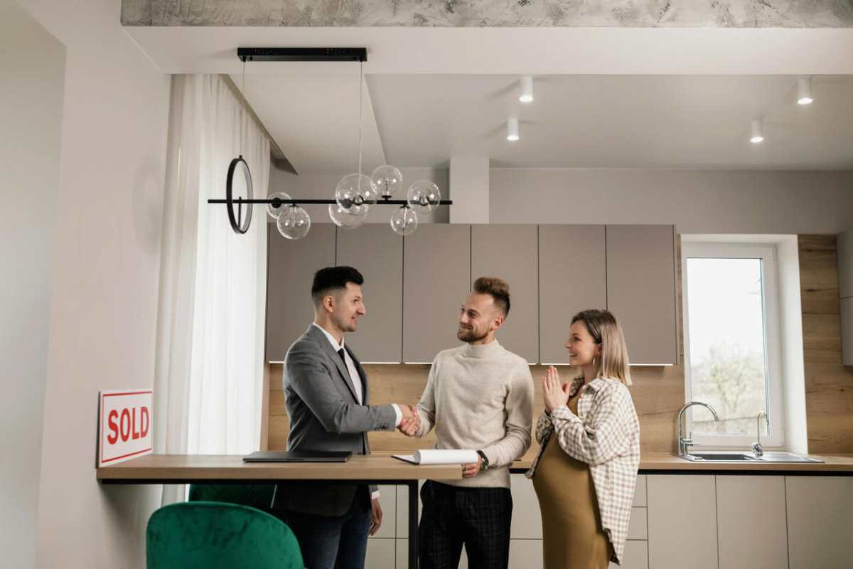 A-smiling-couple-and-a-realtor-finalize-a-house-purchase-in-1.jpg