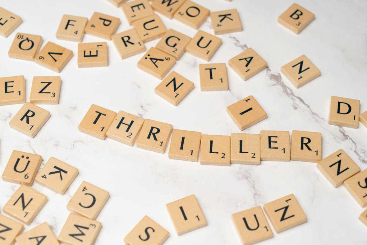 Wooden Scrabble tiles forming the word thriller on a marble surface.