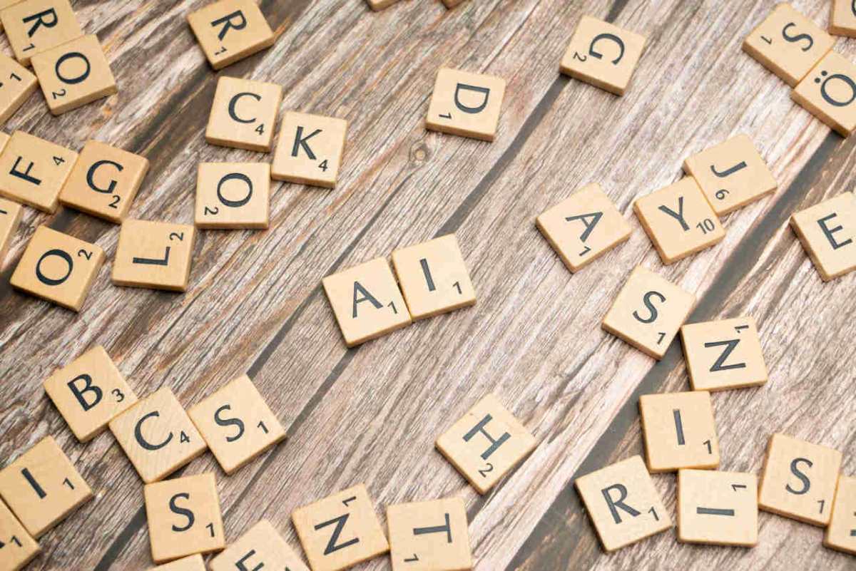 Wooden letter tiles scattered on a textured surface, spelling 'AI'.