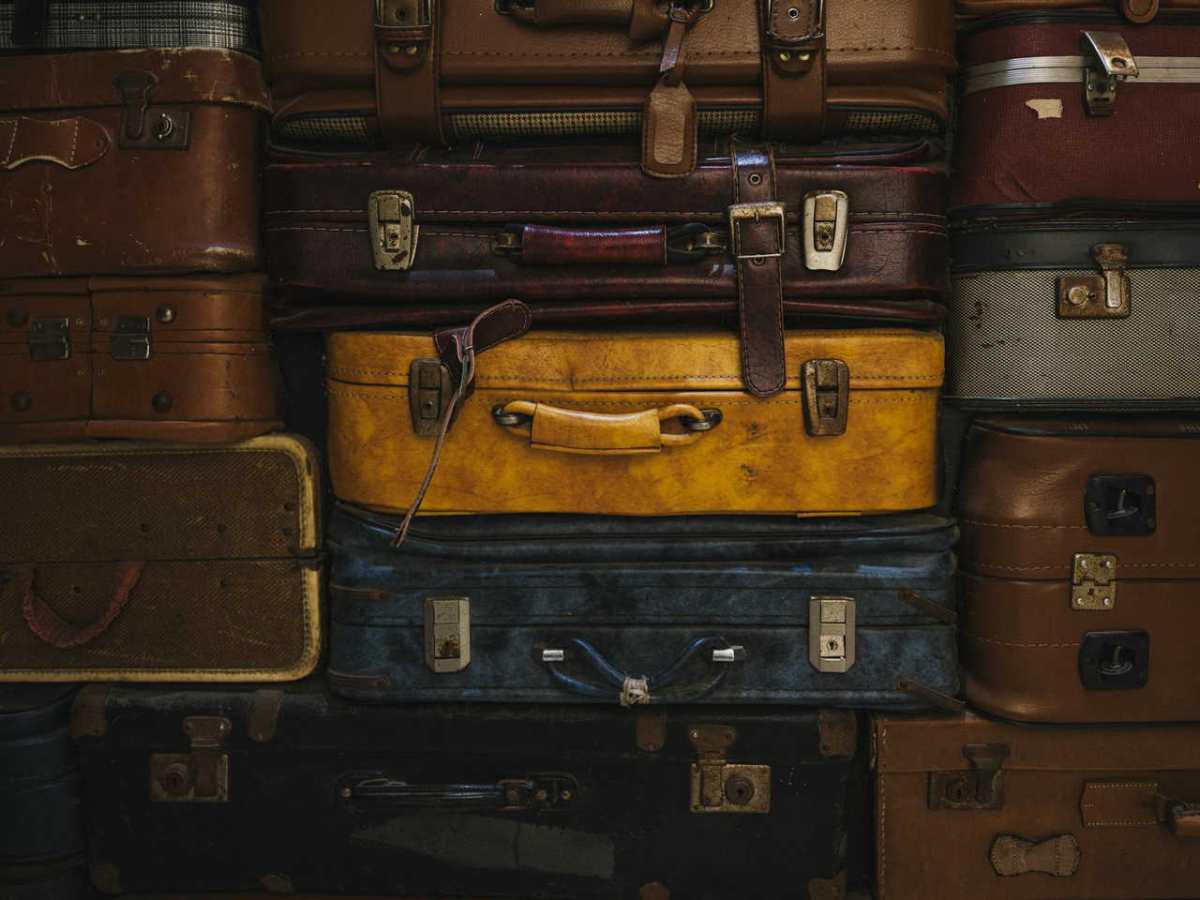 Vintage suitcases stacked in a rustic setting, showcasing classic travel charm.