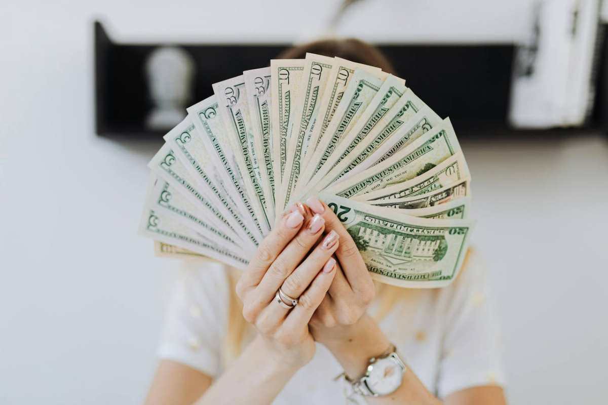Close-up of hands holding a fan of US dollar bills, showcasing financial abundance.