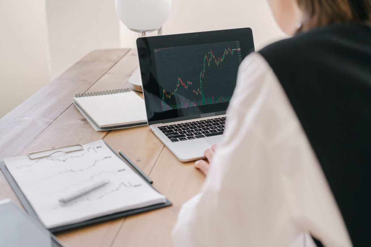 Business professional analyzing stock market trends on a laptop inside an office setting.