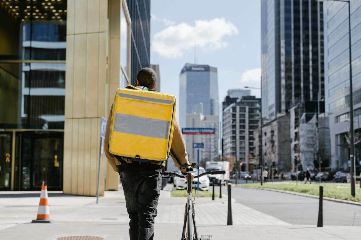 Bicycle courier with large yellow thermal bag delivering food in Warsaw downtown.