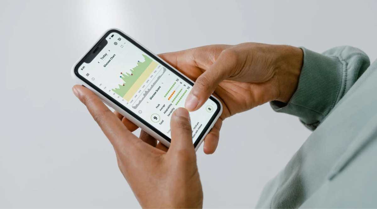 Close-up of hands holding a smartphone showing a health tracking app with charts and data.