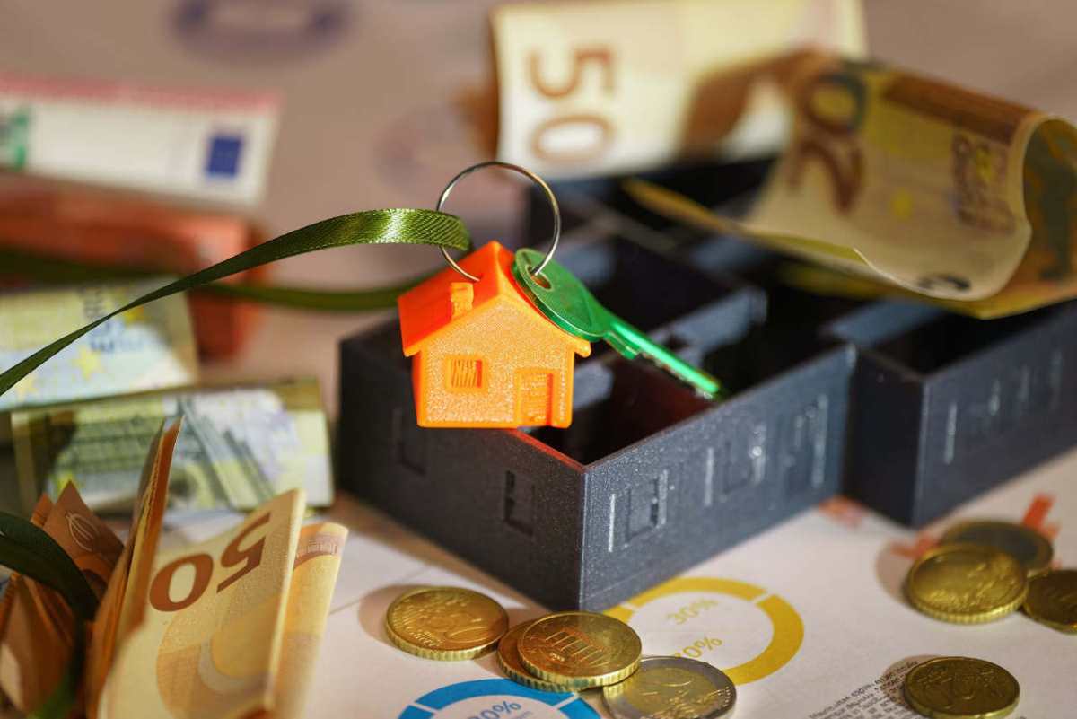 Image depicting real estate investment with keychain, euros, and financial charts.