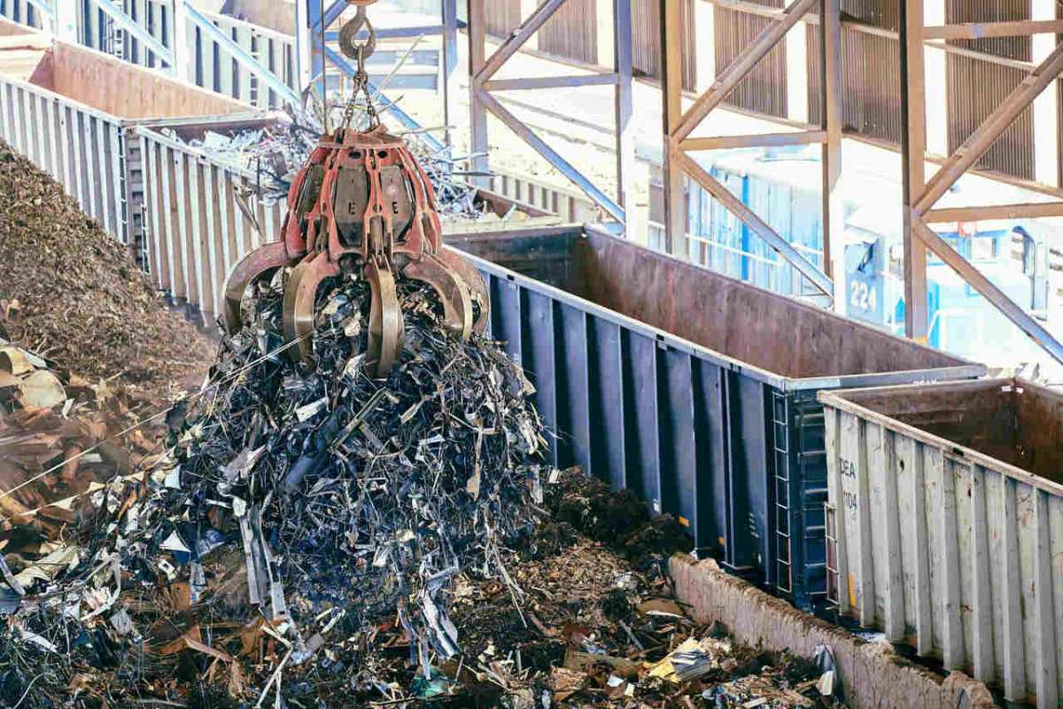 An industrial claw crane lifts metal scrap in a recycling facility, showcasing efficient waste management.