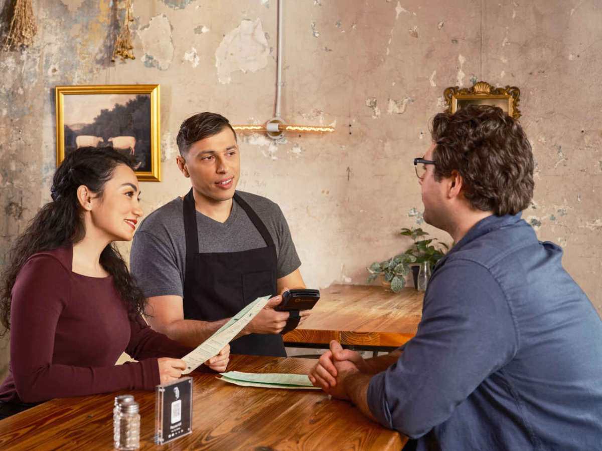 Server uses handheld POS for efficient customer service in a modern restaurant.