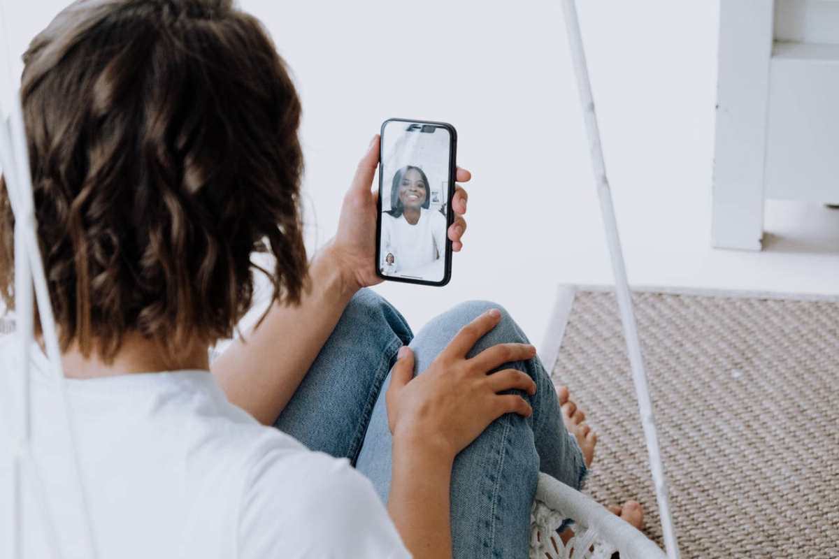 A young woman engages in a cheerful video call with a friend using a smartphone.