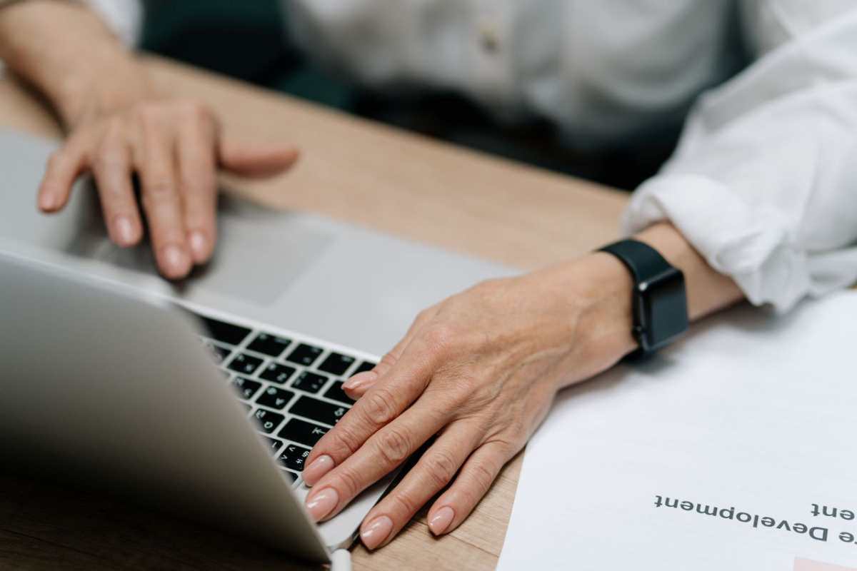 A close-up image of hands with manicured nails typing on a laptop keyboard, showcasing modern workspace.
