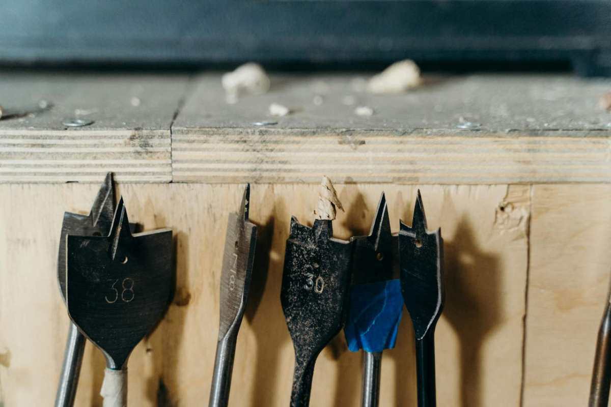 Detailed view of woodworking drill bits on a wooden surface in a workshop environment.