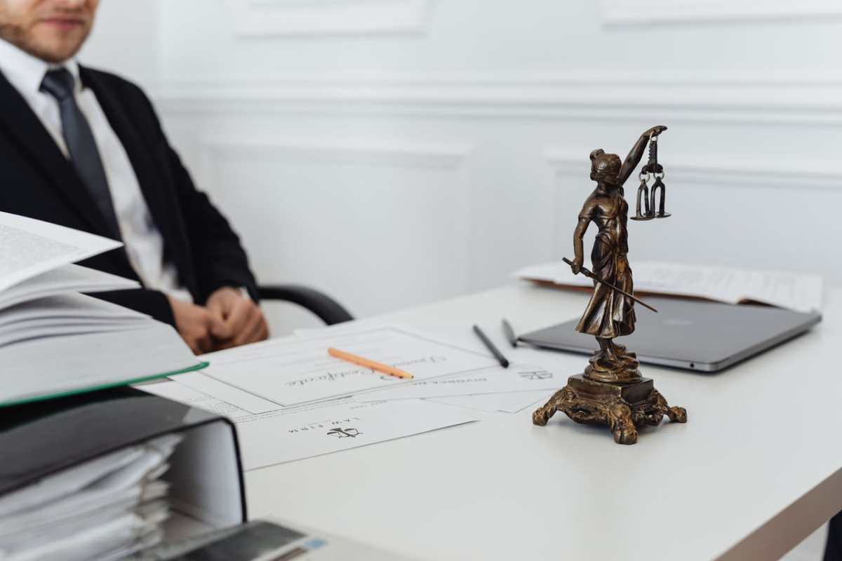 A legal professional's workspace featuring Lady Justice statue, documents, and a laptop.