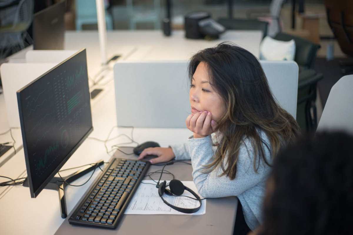 Woman intently viewing a computer monitor in a modern office environment.