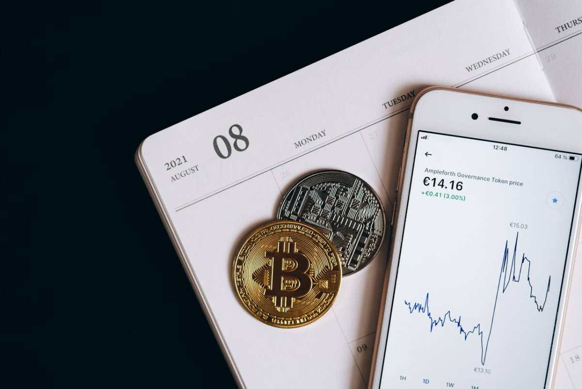 A smartphone displays cryptocurrency data alongside Bitcoin and Ethereum coins on an August calendar.
