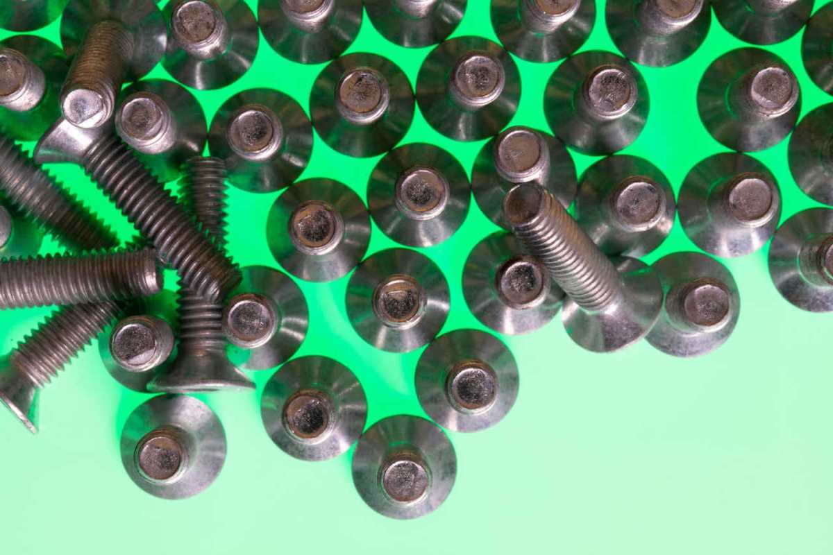 Close-up of metallic screws on a vibrant green surface, symbolizing technology and industry.