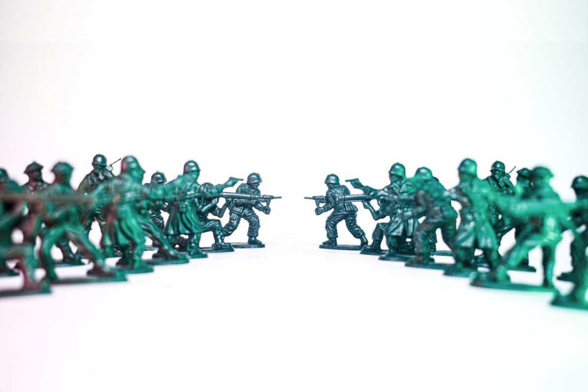 Green toy soldiers facing off on a white background, symbolic of conflict and strategy.