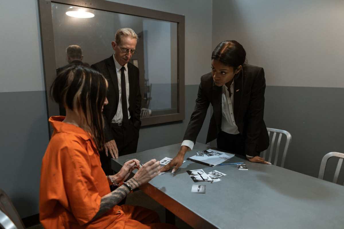 A scene showing a prison interrogation with a detective and inmate at a table.