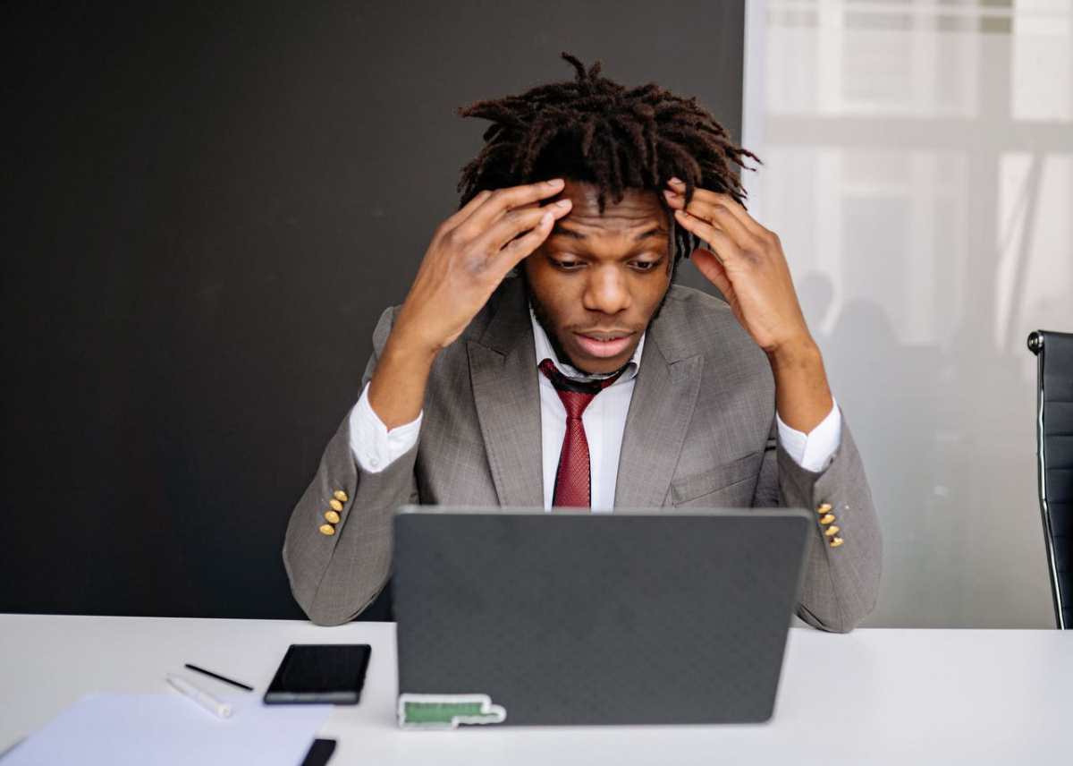 African American businessman experiencing stress while working on a laptop indoors.