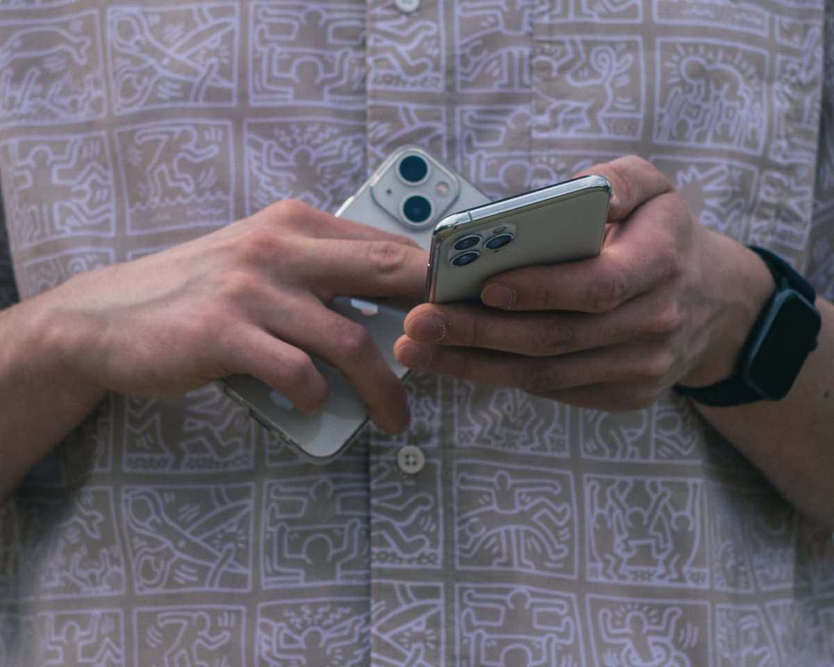 Detail of hands holding two smartphones, showcasing modern technology usage.