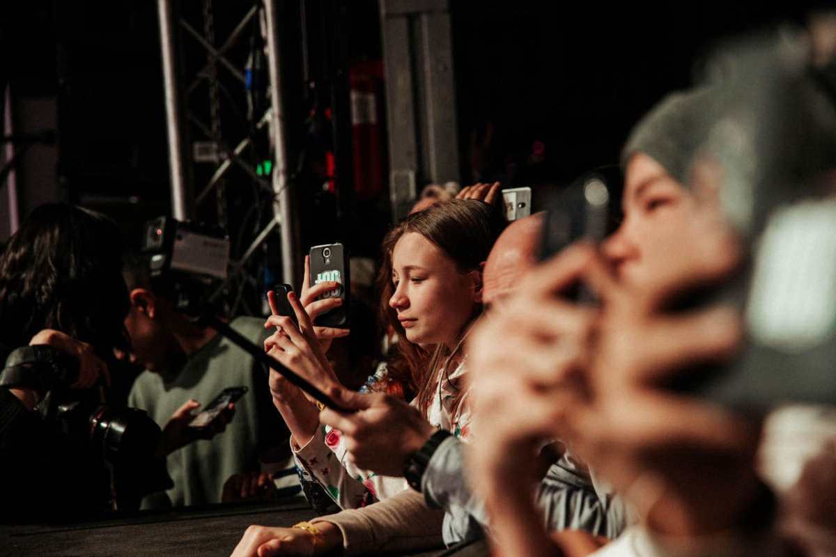 People eagerly capturing a live event on their smartphones, showcasing audience engagement.