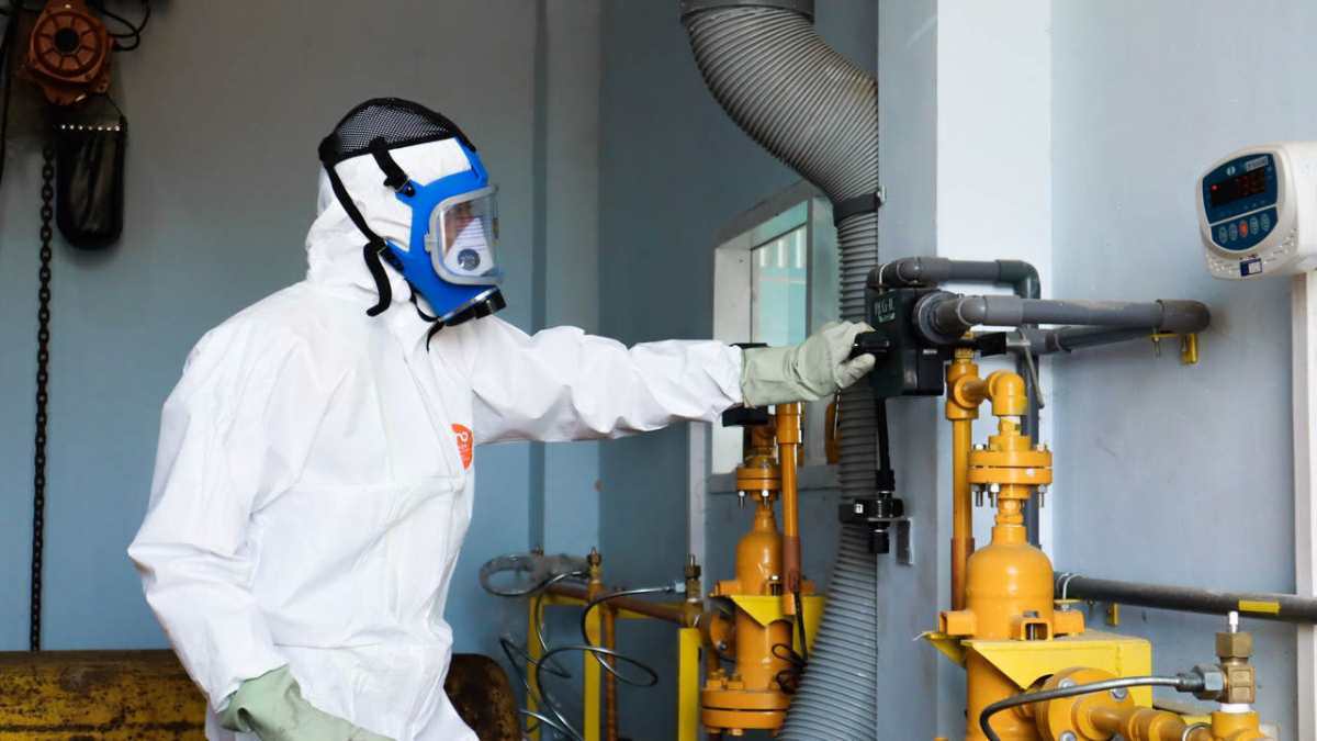 Industrial worker in protective gear inspecting machinery for safety compliance in Indonesia.