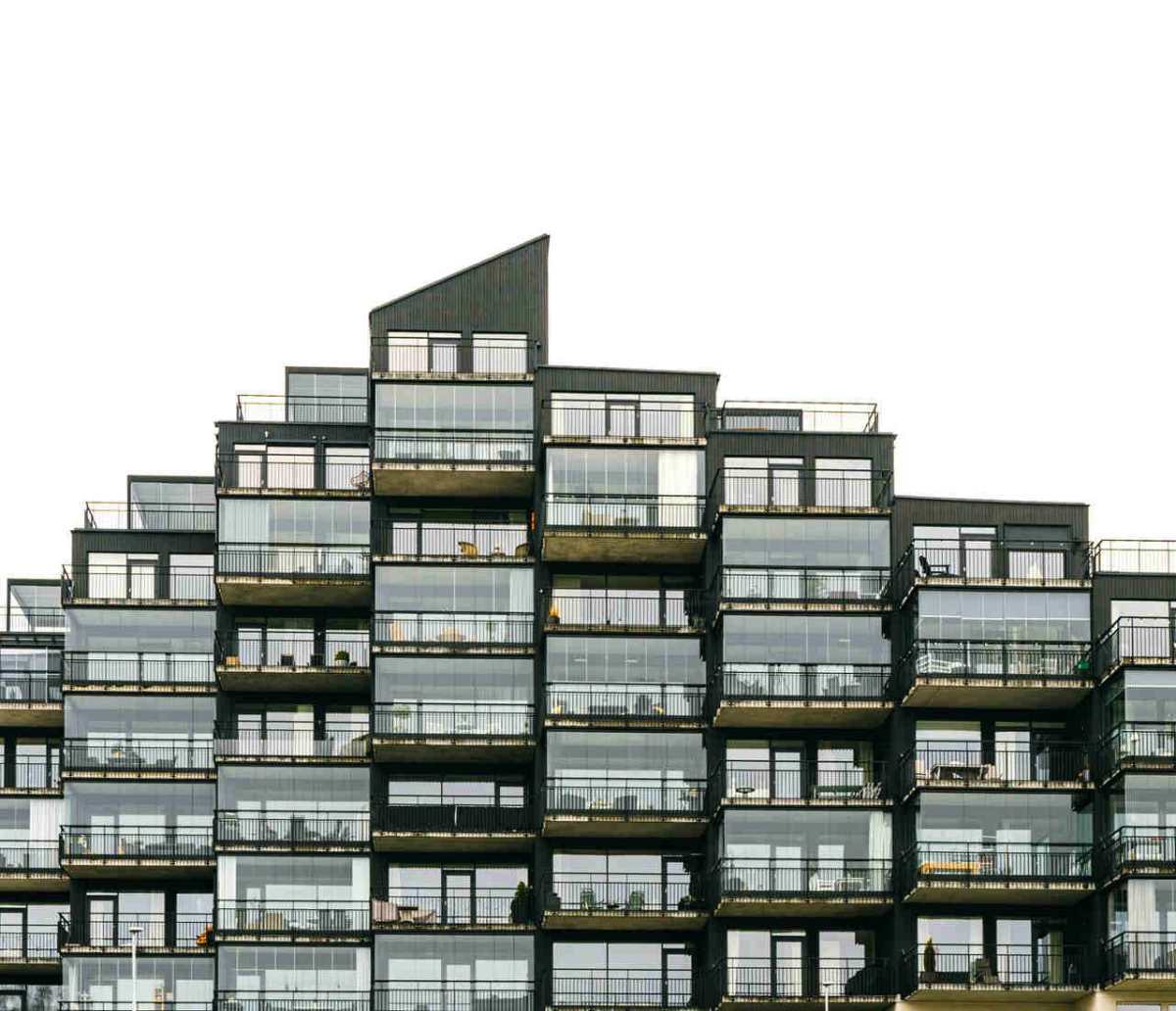 Contemporary apartment building with geometric facade and glass balconies, showcasing modern architecture.