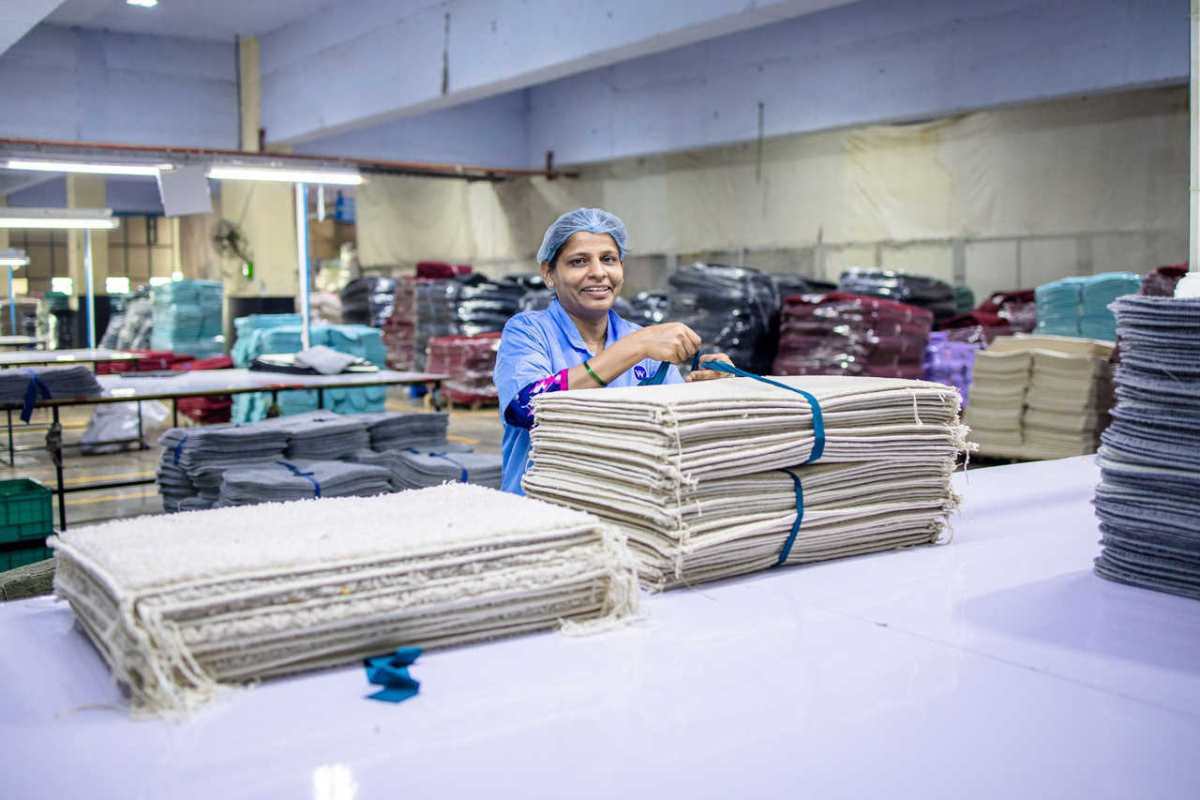 A textile factory worker organizing stacks of fabric indoors. Bright and cheerful environment.