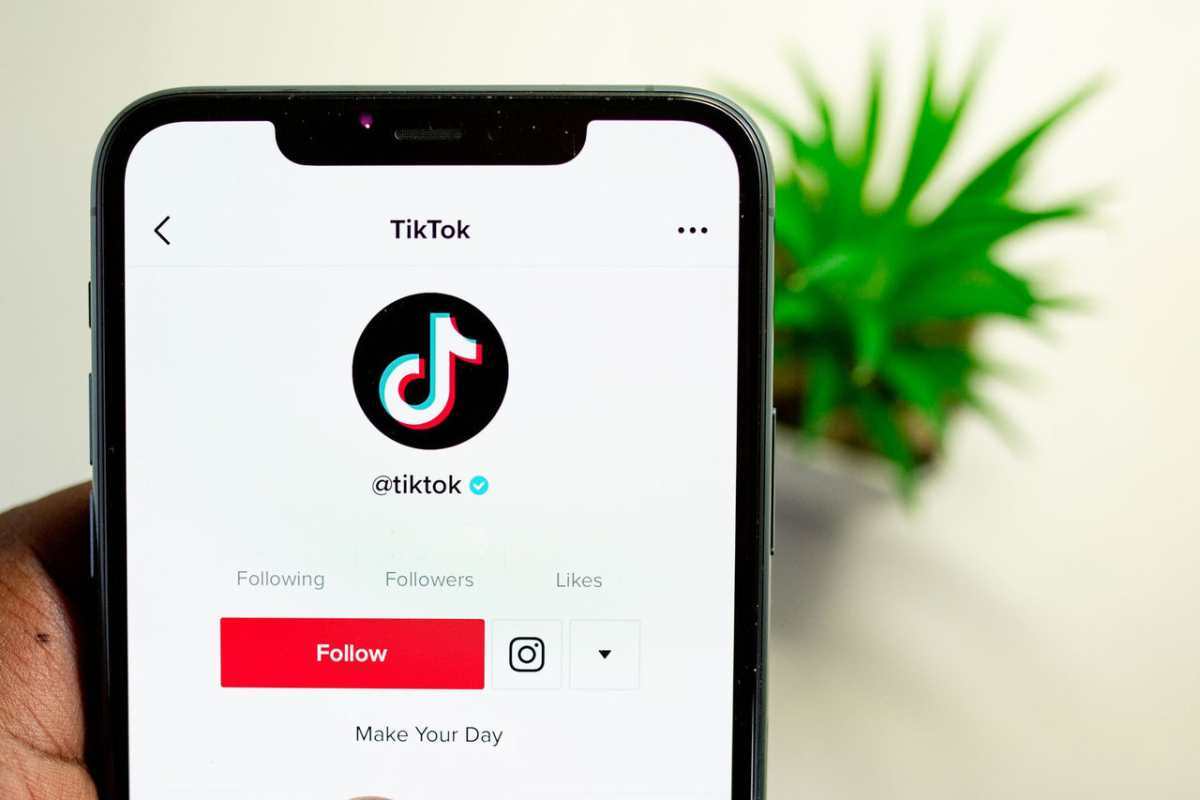 Close-up view of hand holding smartphone displaying TikTok app interface with profile page.