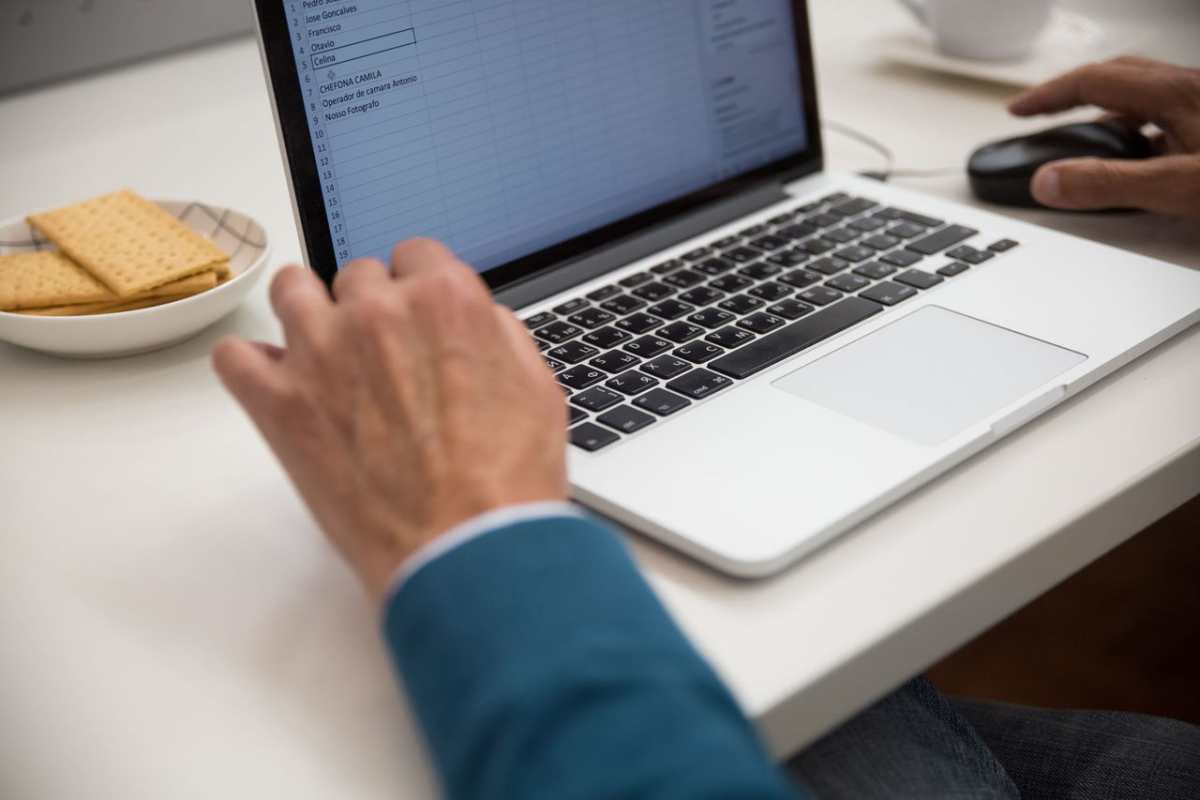 A person working on a laptop at a desk with snacks, emphasizing productivity and technology.