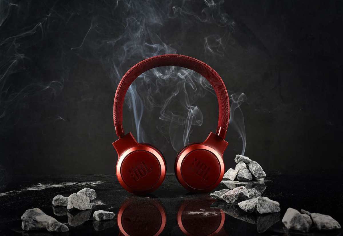 Red JBL headphones with a smoky and rocky dark studio backdrop.