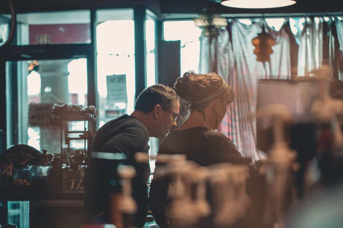 Two small business owners engaged in conversation within a warm, inviting cafe setting.
