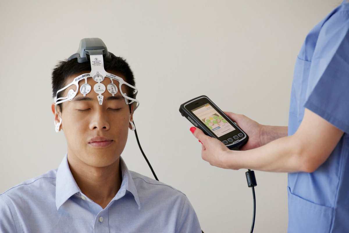 Healthcare professional conducting an EEG examination using a Brainscope device on a male patient.