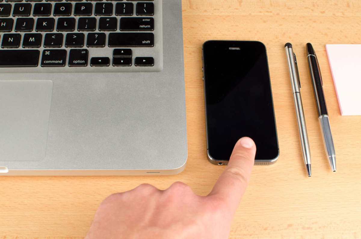 Close-up of a workspace with a laptop and smartphone on a wooden desk.