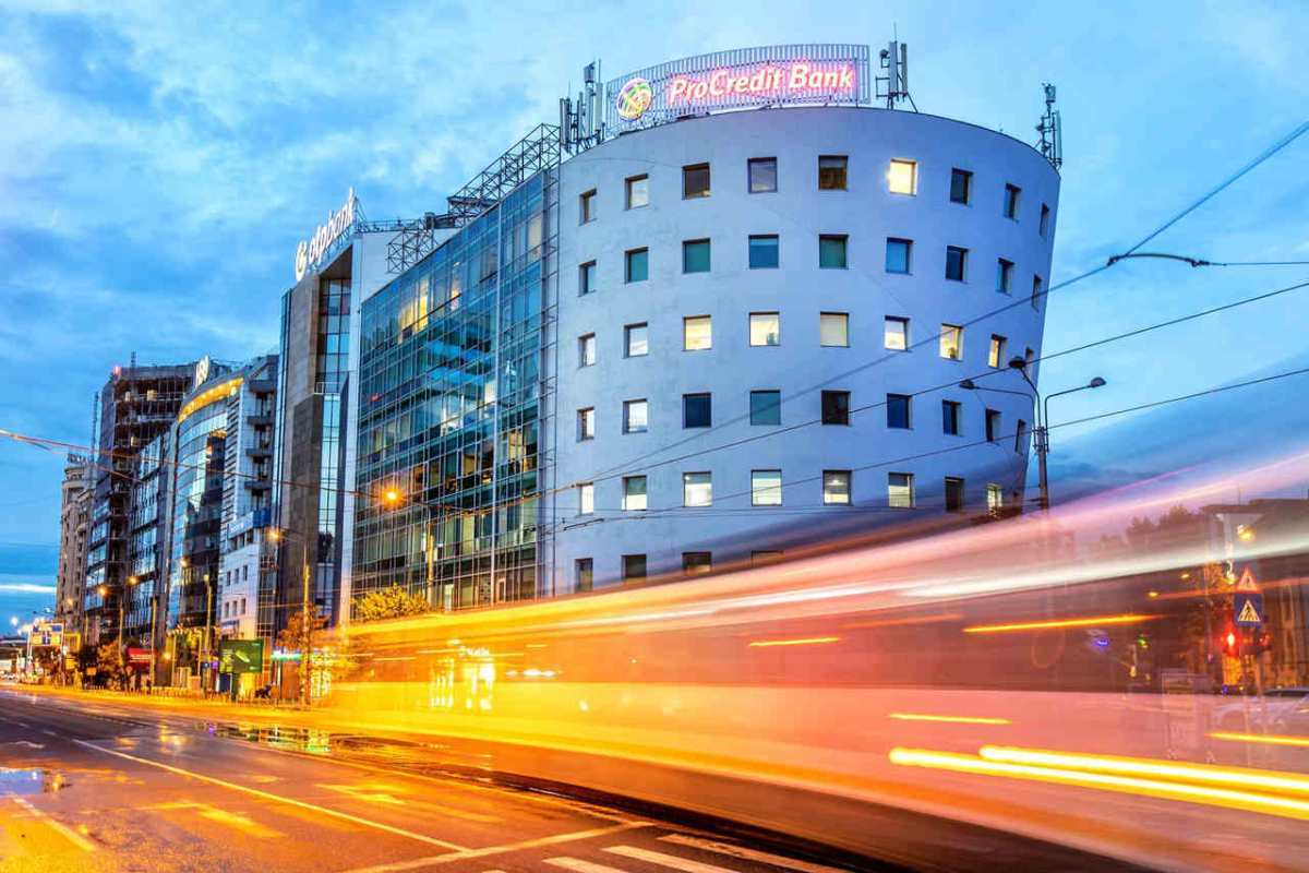 Street view of modern buildings and light trails in Bucharest during evening.