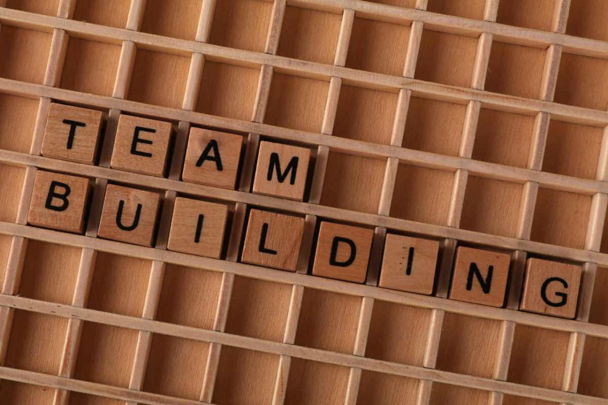 Wooden letter tiles spelling 'Team Building' on a grid surface to symbolize collaboration.