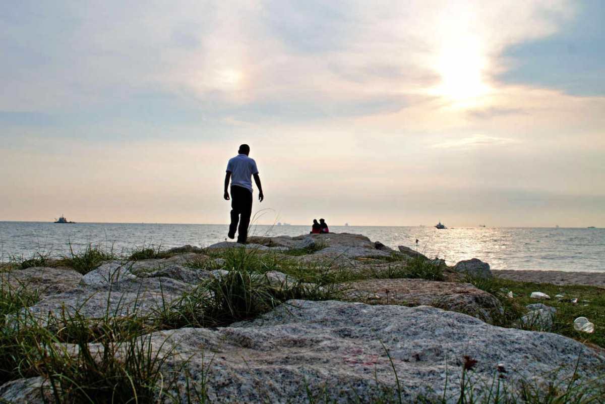 A serene seaside scene at Tanjung Kling, Malacca, showcasing a sunset over the rocky shore.