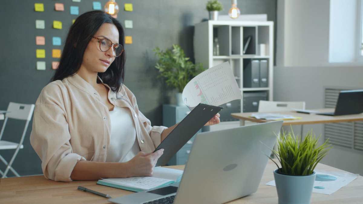 Woman in office reviewing documents and charts, focusing on business growth.