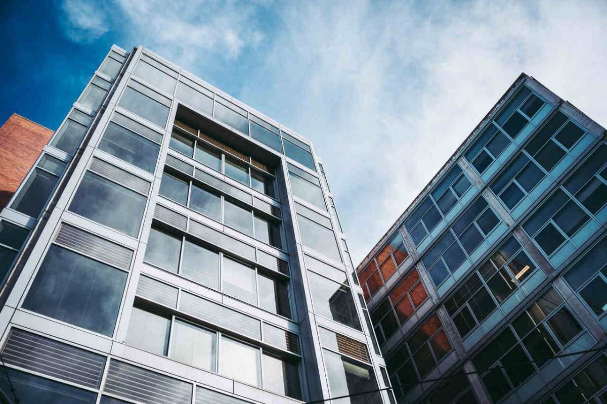 From below of facades of modern buildings in residential district under cloudy blue sky in daytime