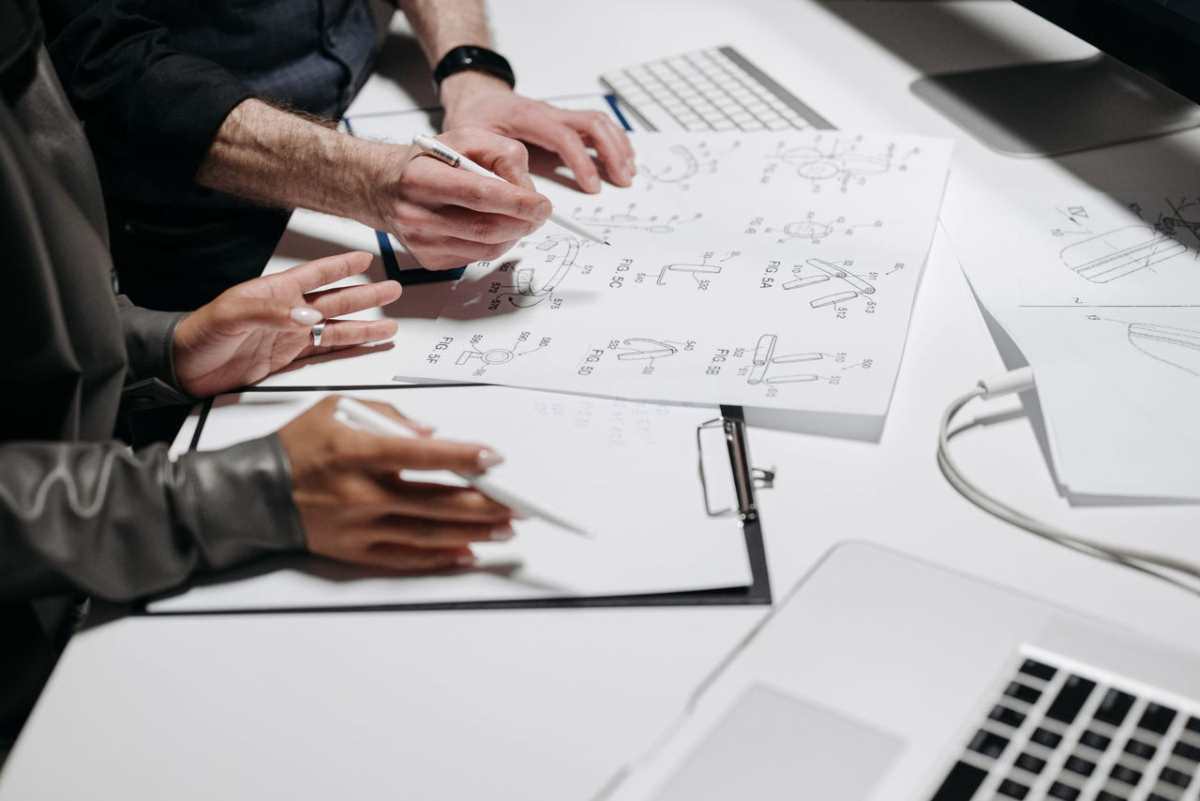 Team members analyzing technical schematics on office workspace. Ideal for business and engineering concepts.