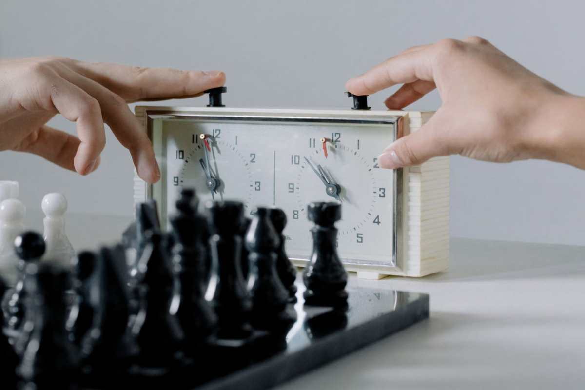 Close-up of hands pressing chess clock during an intense board game session.