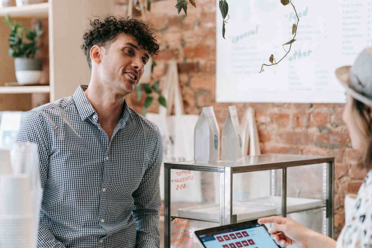 Customer smiling during a pleasant conversation in a cozy coffee shop with exposed brick walls.