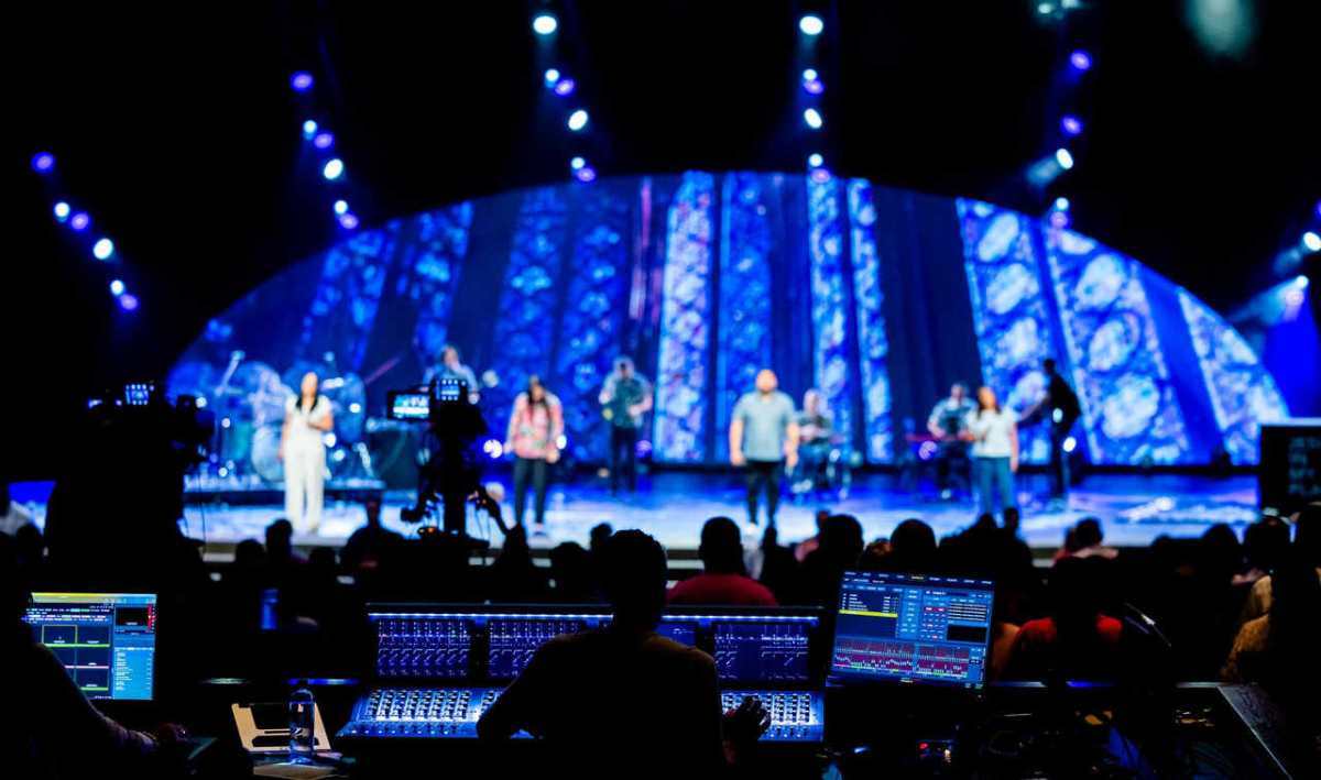 Stage performance with band, vibrant lighting, and audience at a live concert event.