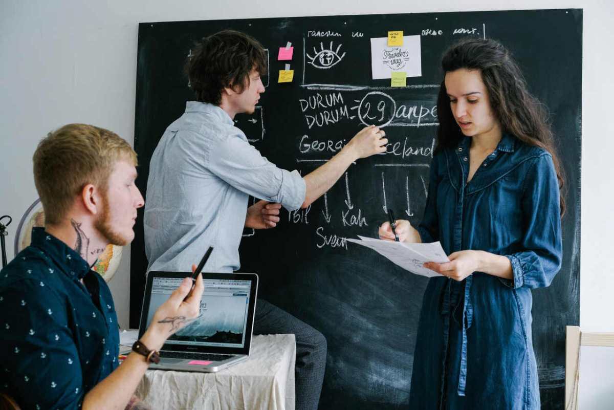 Young professionals collaborating on a project at a blackboard in a creative office environment.