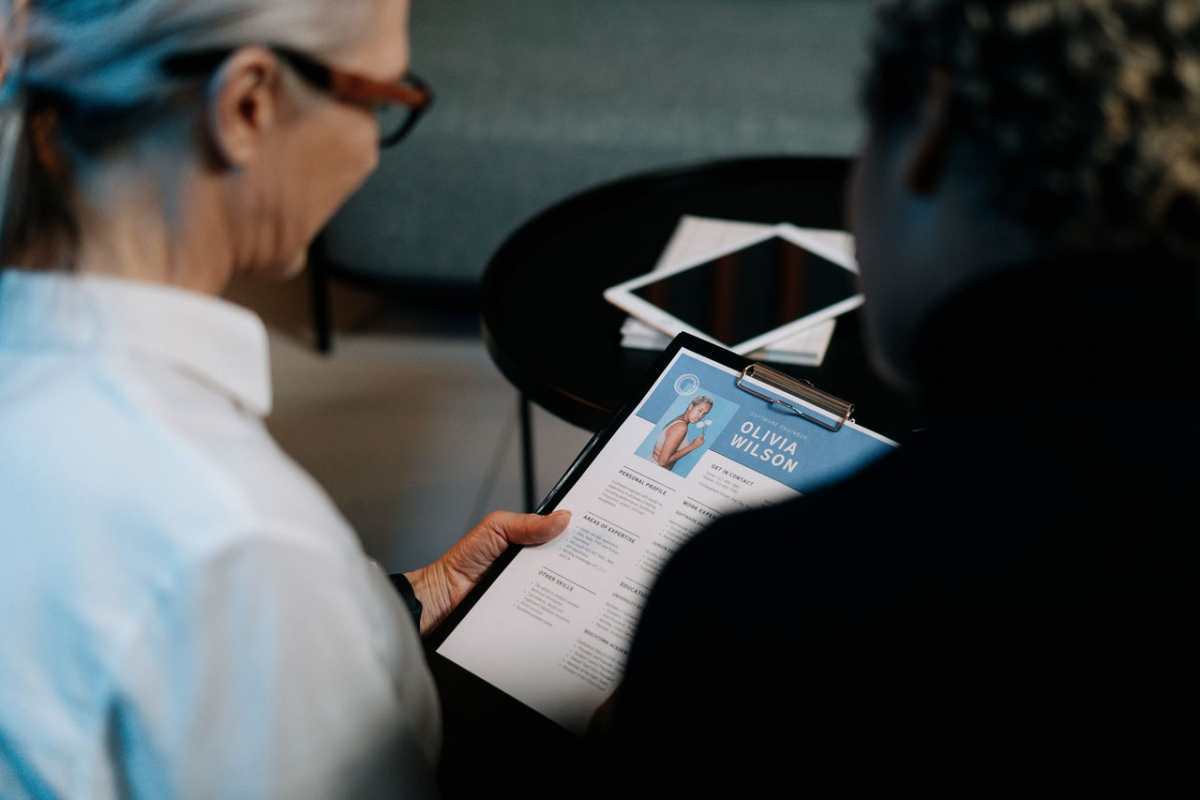 Business professionals conducting an interview with resume on clipboard in an office setting.