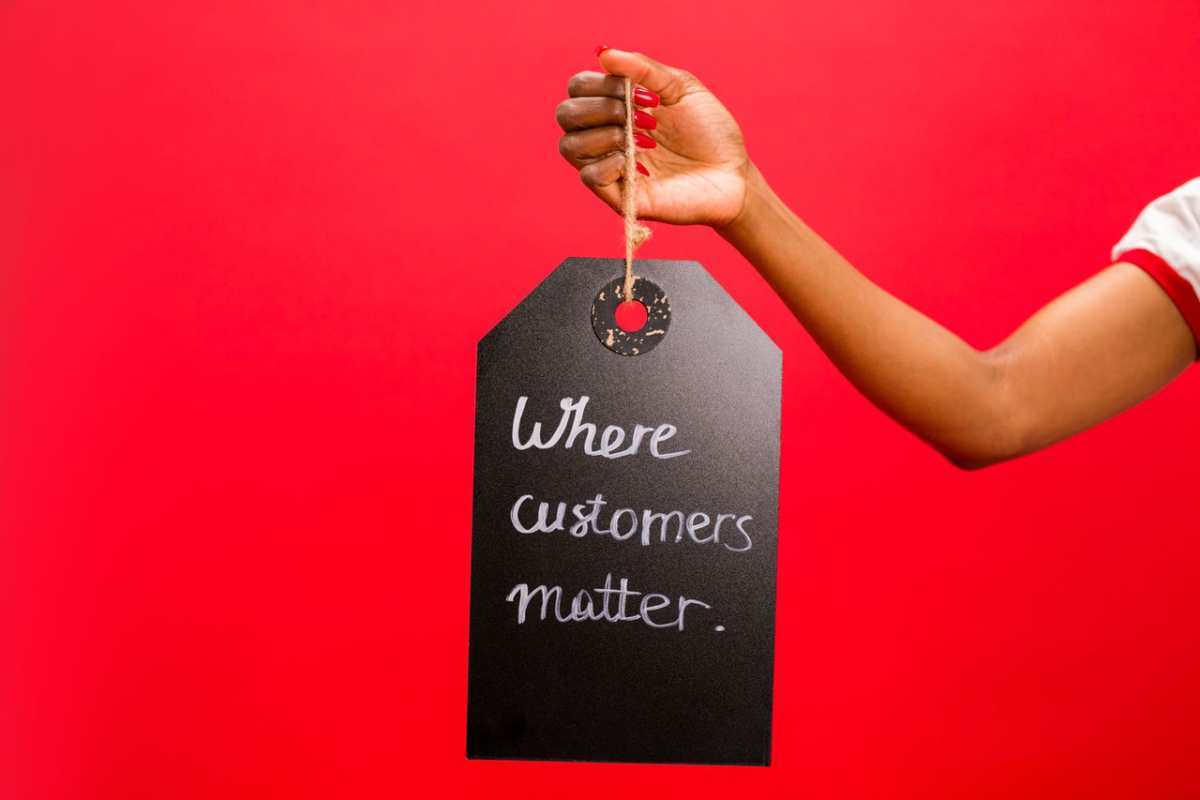 A hand holding a tag with 'Where customers matter' text on a vivid red background, emphasizing customer service.