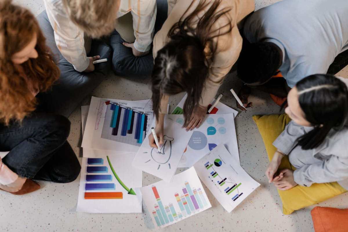 Overhead view of diverse team brainstorming on business strategy using charts and graphs.