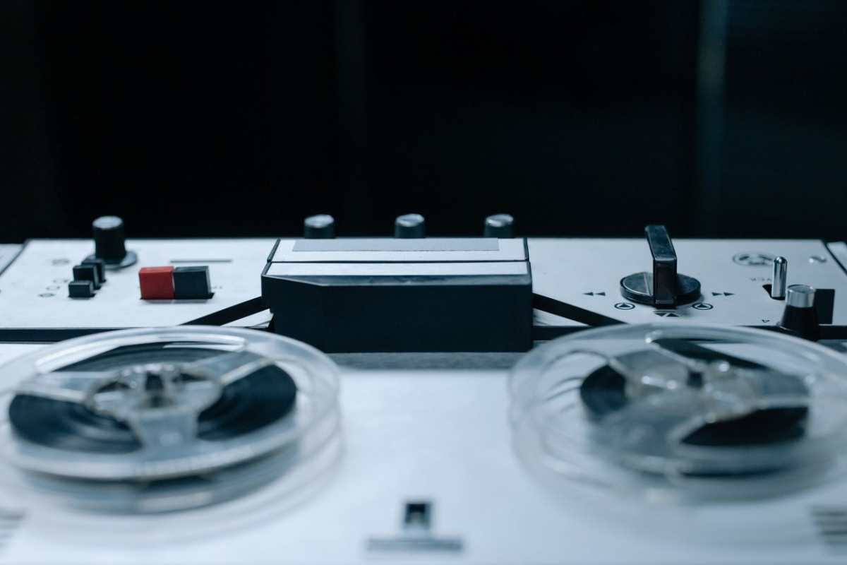Close-up image of a vintage reel-to-reel audio recorder with control buttons and tape reels.